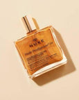 Nuxe Huile Prodigieuse Or: Shimmering Golden Dry Oil for Face, Body & Hair - Natural Multi-Purpose Illuminating Oil Nuxe Huile Prodigieuse Or: Shimmering Oil for Radiant Skin & Hair Nuxe Huile Prodigieuse Or, shimmering dry oil, golden shimmer oil, multi-purpose oil, natural beauty oil, face body hair oil, illuminating oil, pariltili kuru yag, altin pariltili yag, cosmetic oil, face oil, body oil, hair oil, natural ingredients, shimmering oil, golden oil, radiant skin, luminous skin, dry oil, non-greasy, hy