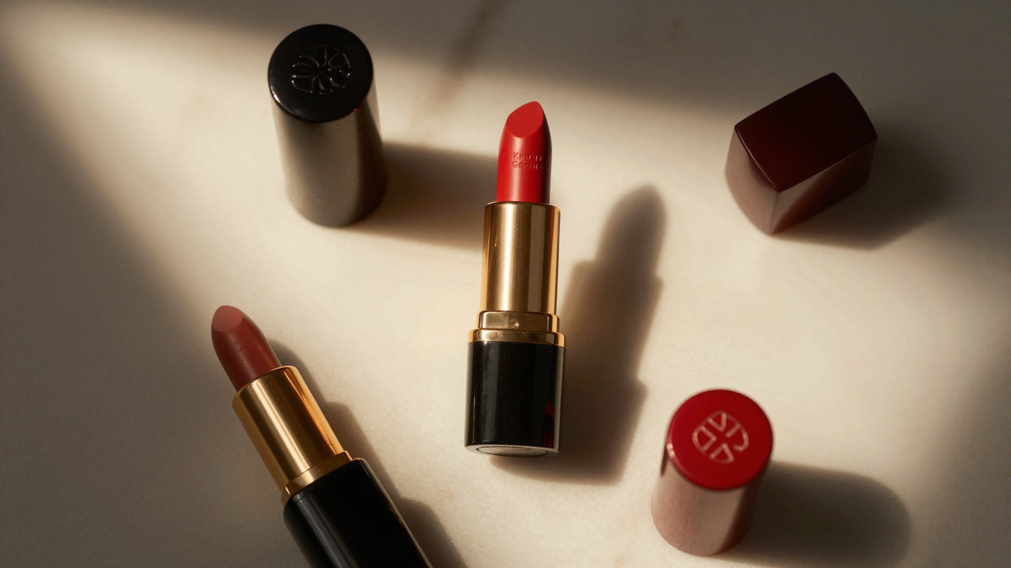 Luxury lipstick tubes in red and nude shades on marble