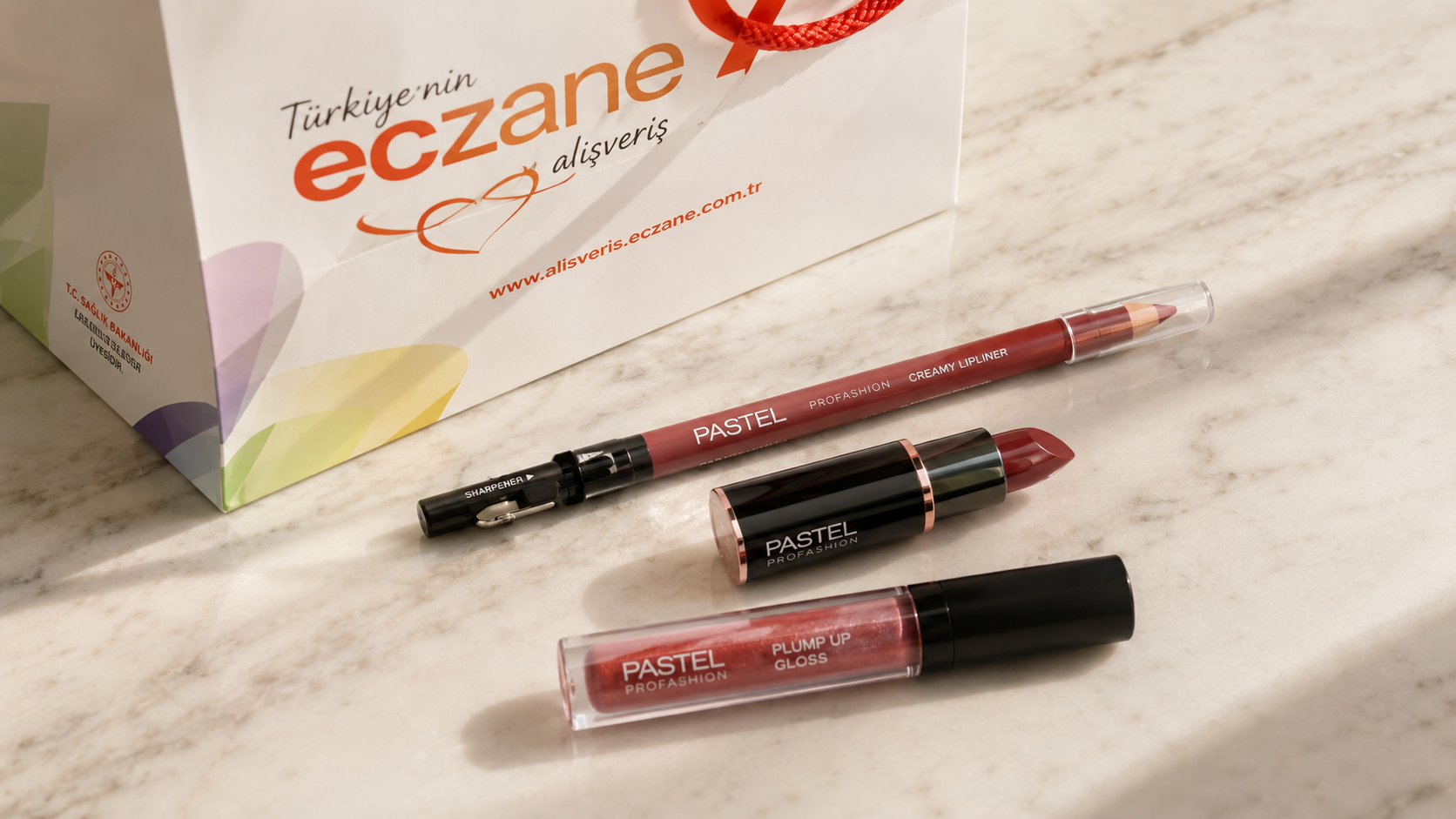 Flat lay of lip liner, lipstick, and gloss with a pharmacy bag