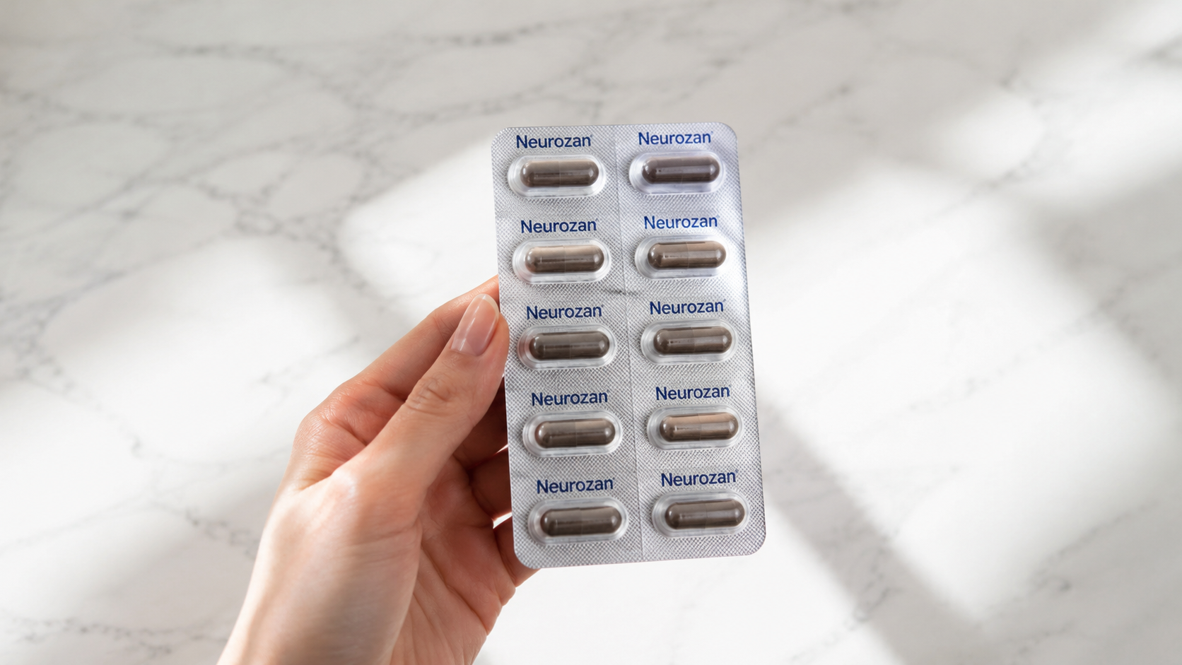 Hand holding a Neurozan supplement pack with soft morning light