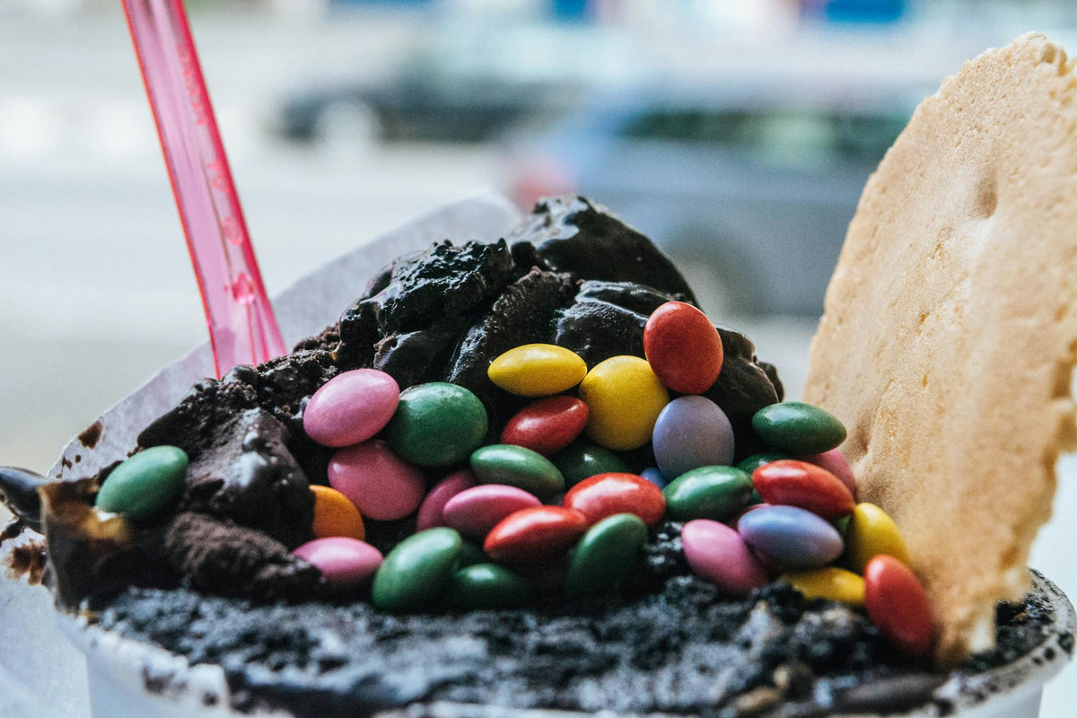 Close-up of a chocolate ice cream topped with multicolored candies and a waffle wafer.