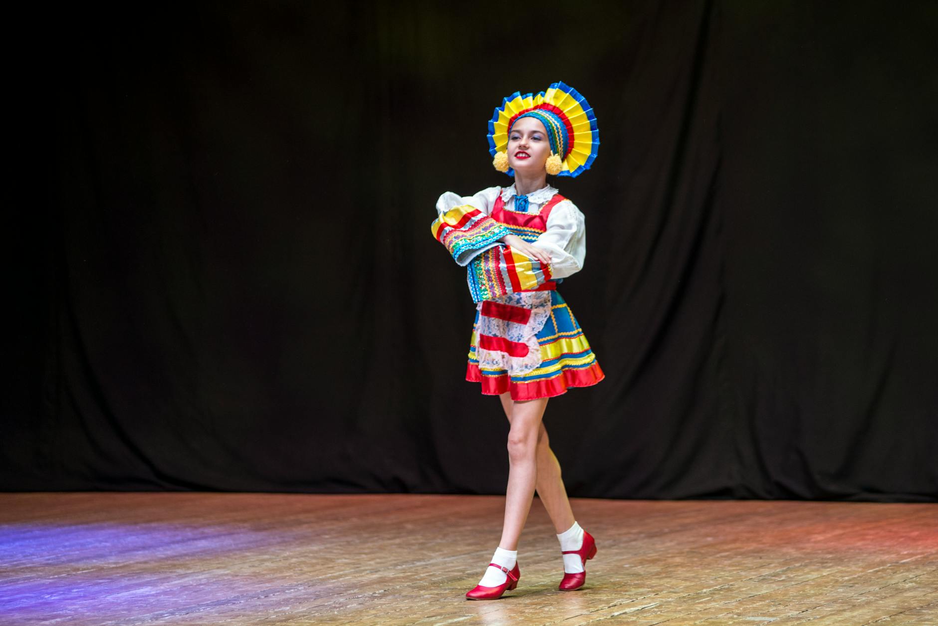 Colorful folk dancer performing on stage in traditional costume.