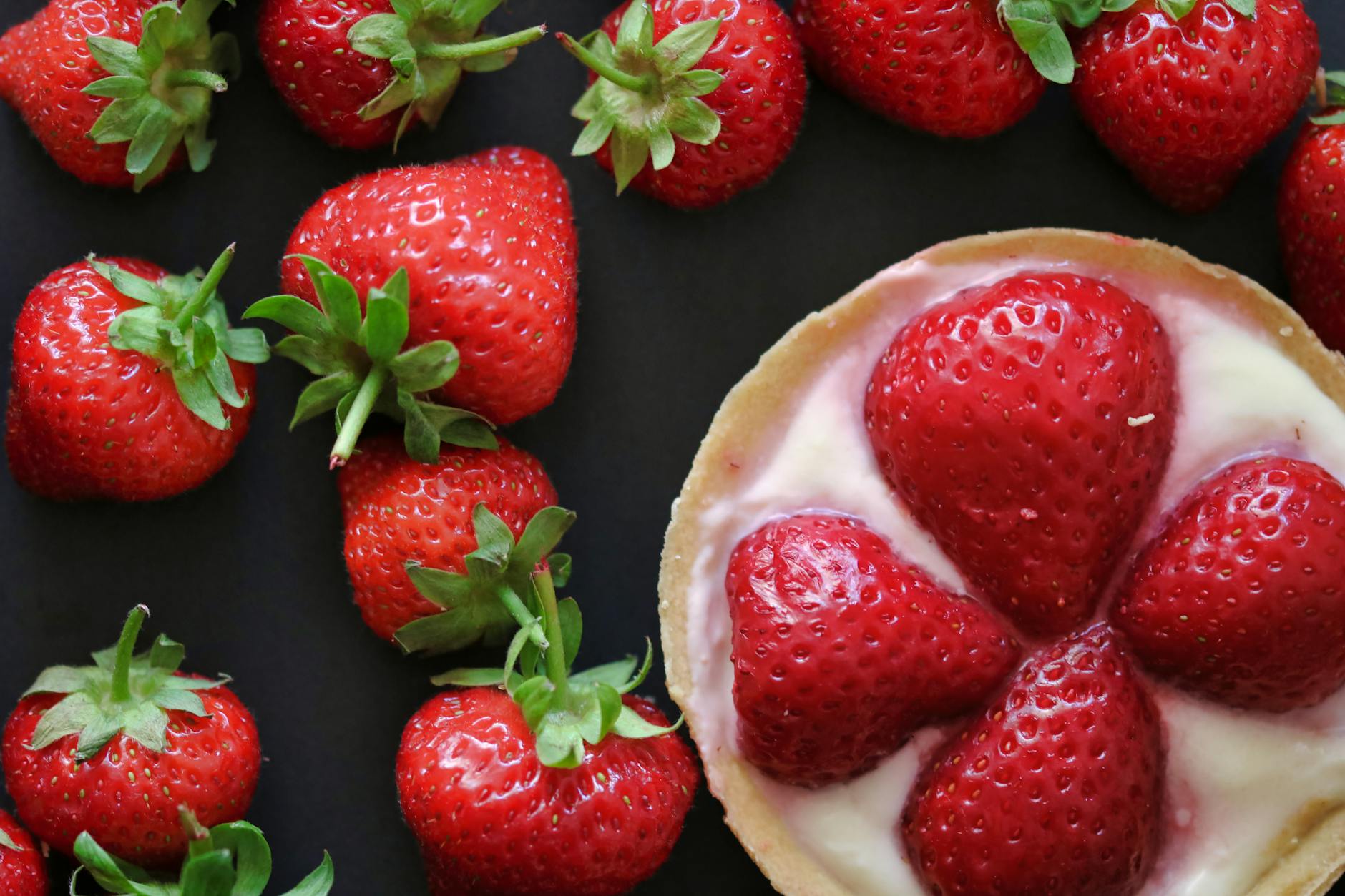 Top view of fresh strawberries and a delicious cream tart, emphasizing freshness and sweetness.