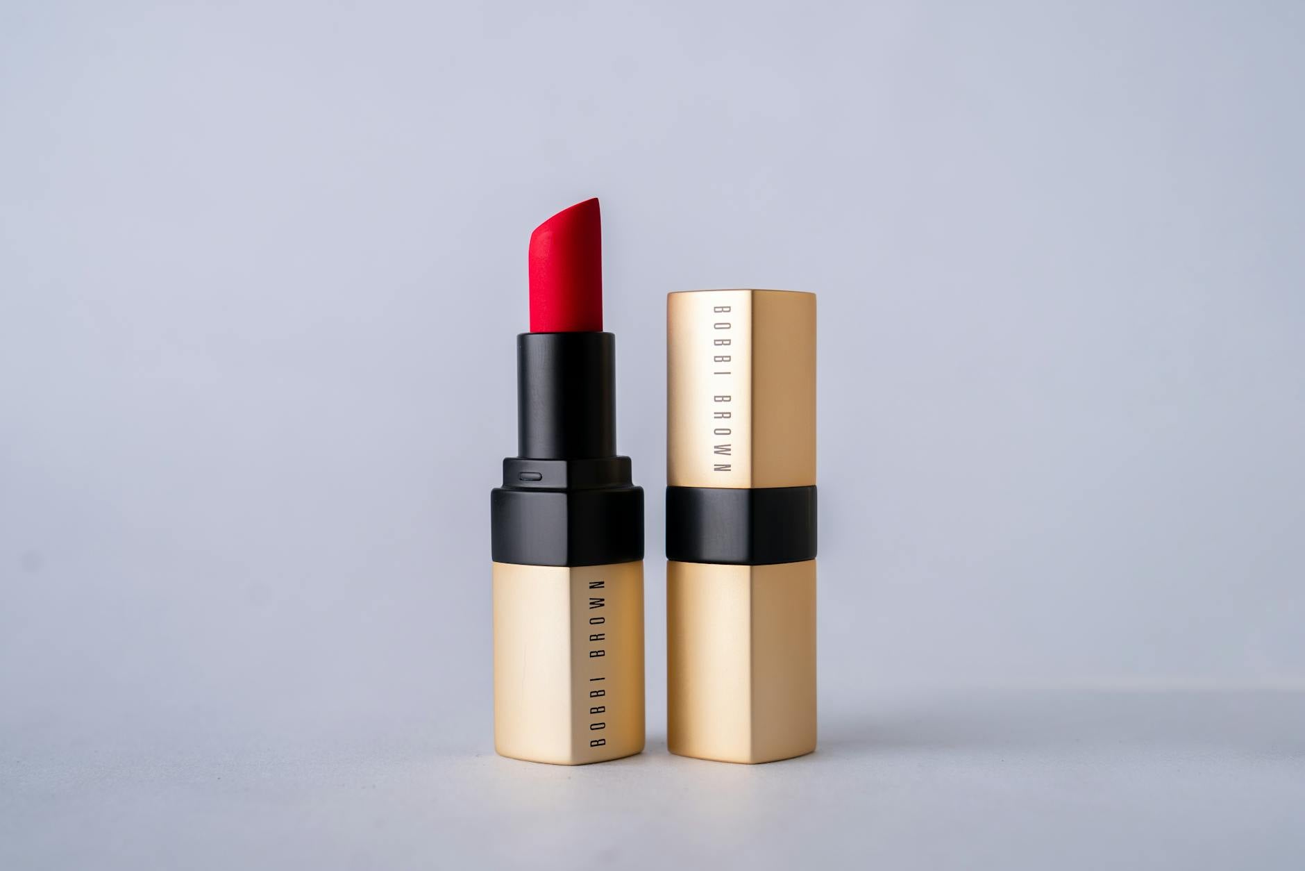 Elegant red Bobbi Brown lipstick photographed against a minimalist gray background.