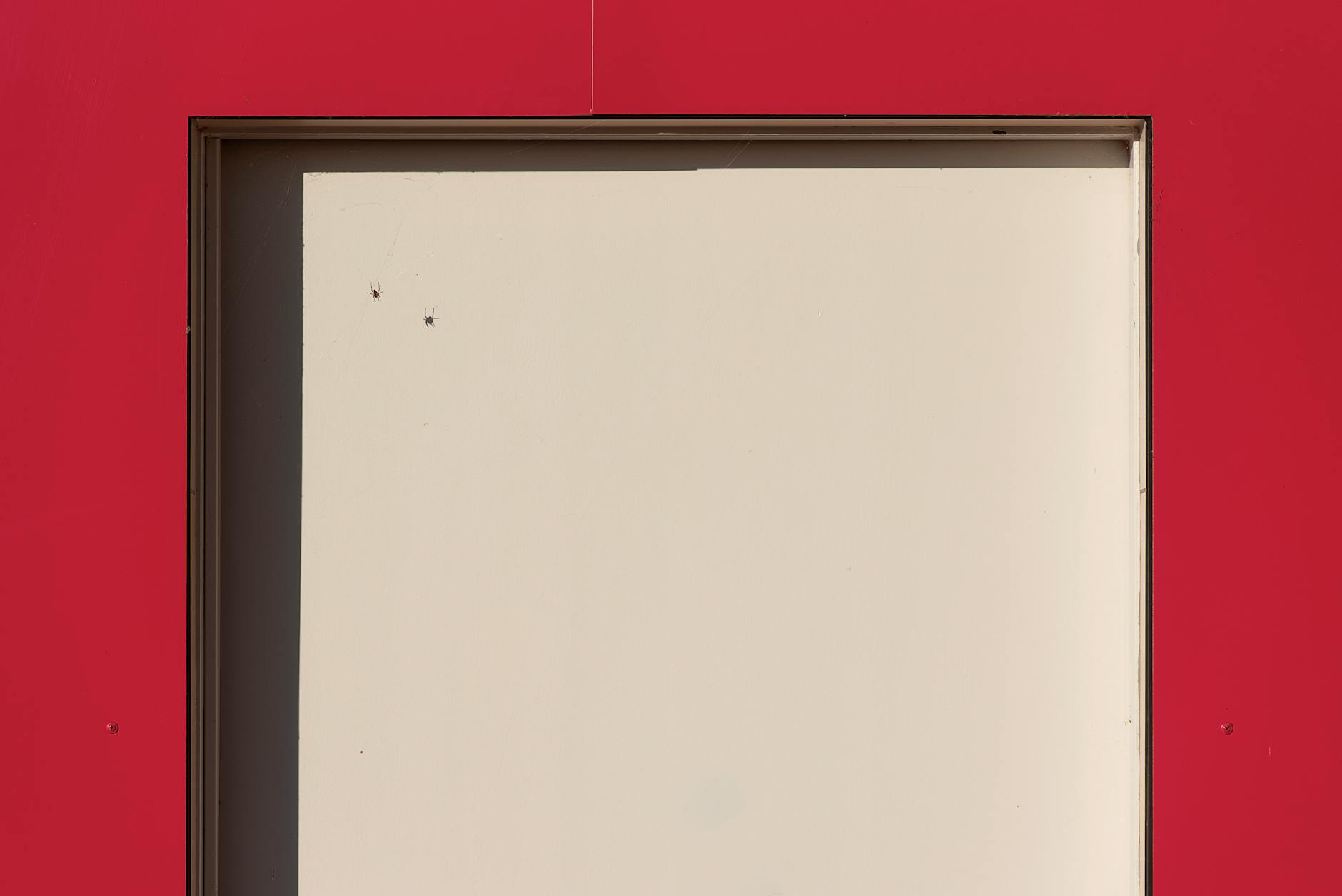 A minimalist architectural shot of a red and beige doorway with geometric composition.