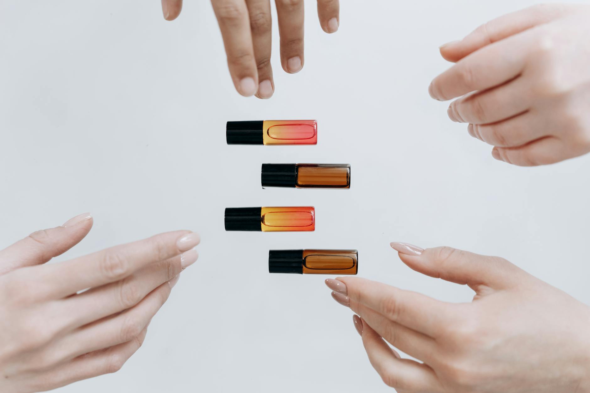 Hands gracefully displaying a set of colorful essential oil bottles.