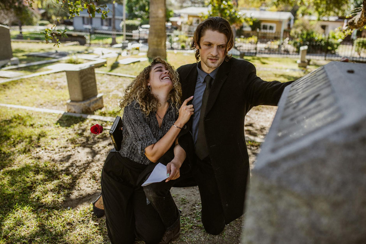 A grieving couple at a cemetery, expressing deep sorrow and loss.