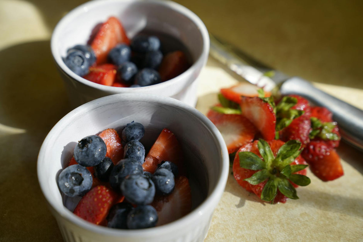 Delicious blueberries and strawberries in ceramic bowls with natural light.