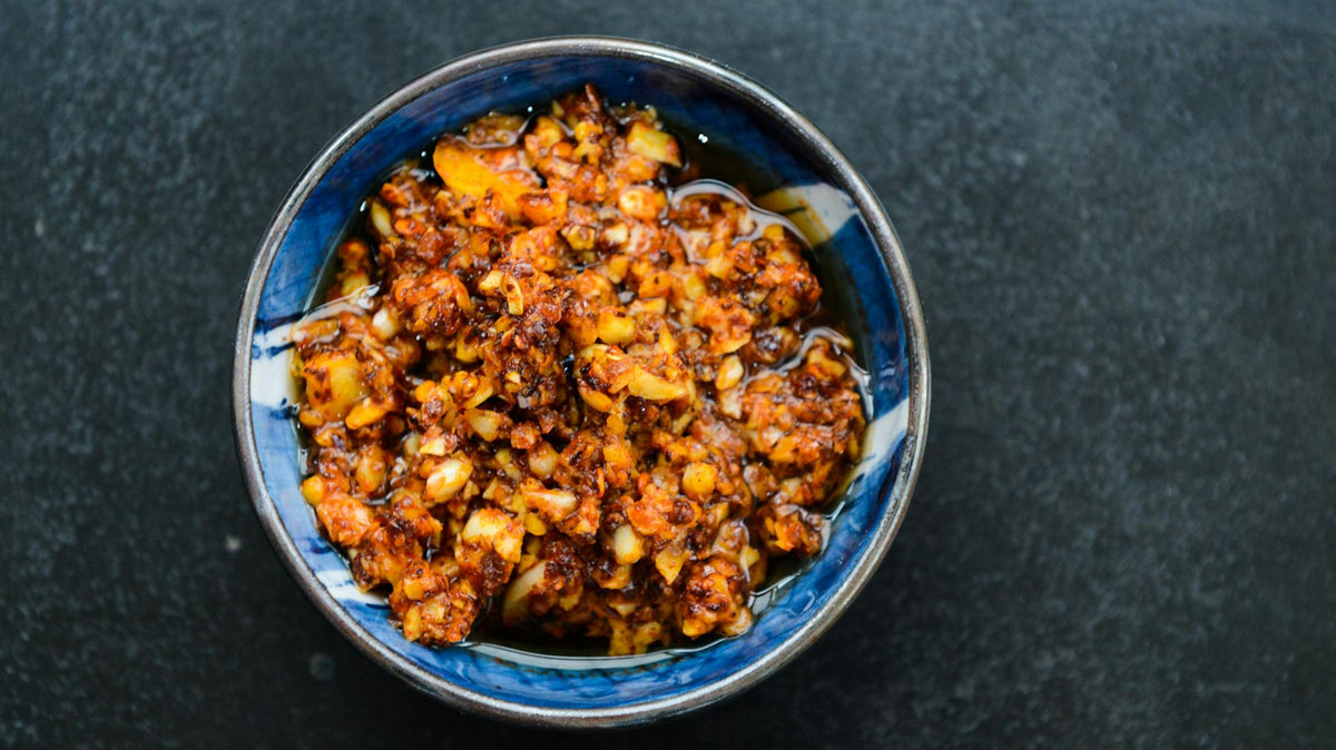 A vibrant bowl of spicy chili oil with garlic and pepper flakes, ideal for enhancing meals.