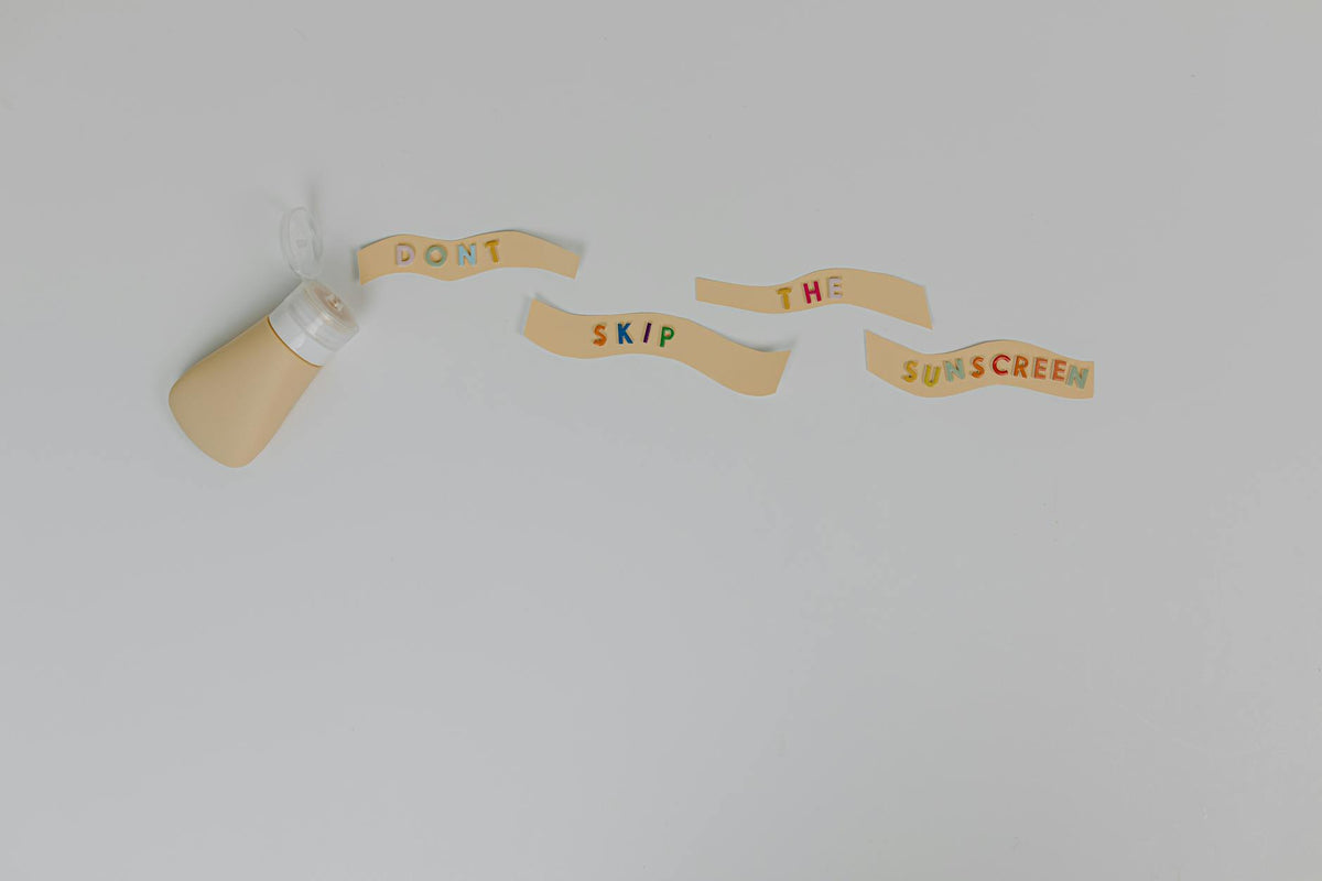 Sunscreen bottle and creative text 'Don't Skip the Sunscreen' on white background, promoting skincare and cancer prevention.